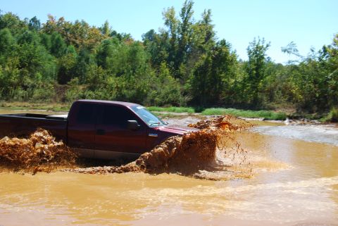 2005 Ford F-150 - Pickup truck driving through a muddy water crossing.