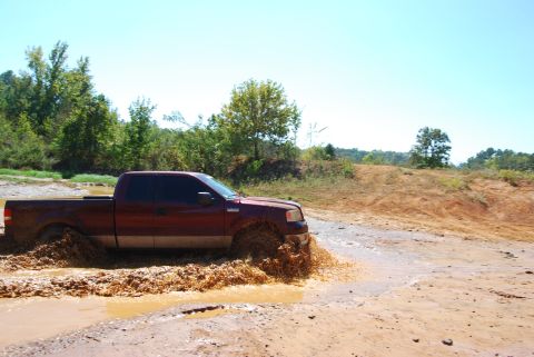 2005 Ford F-150 - This truck is navigating a challenging off-road course with deep mud and water.