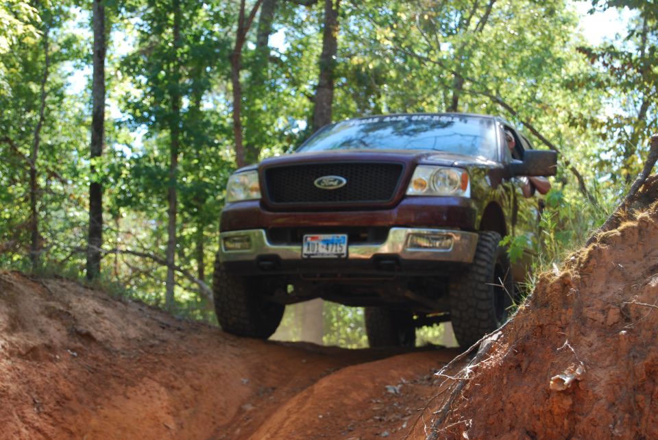 2005 Ford F-150 driving on a dirt trail with trees in the background