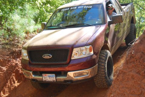 2005 Ford F-150 - Ford F-150 off-roading on a muddy trail with aggressive tires.