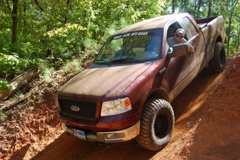 2005 Ford F-150 - A maroon Ford F-150 navigates a steep dirt path during an off-road excursion.