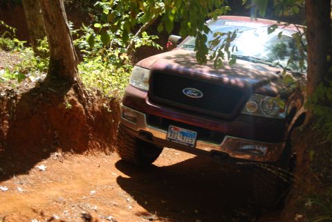 2005 Ford F-150 - A maroon Ford F-150 navigates a dirt path surrounded by trees.