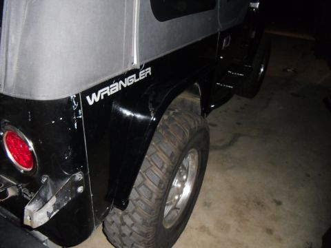1992 Jeep Wrangler - Rear fender detail of a black 1992 Jeep Wrangler, showing the side profile and "Wrangler" badging.