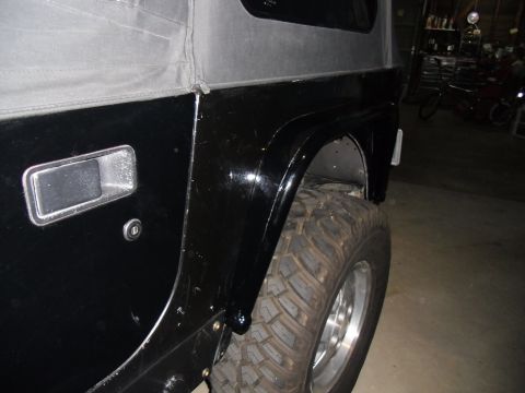 1992 Jeep Wrangler - The rear fender and tire of a black Jeep Wrangler are visible from the side.