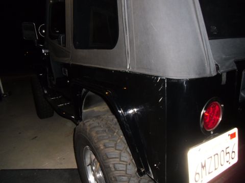 1992 Jeep Wrangler - Rear view of a black 1992 Jeep Wrangler, showing the fender, tire, and license plate.