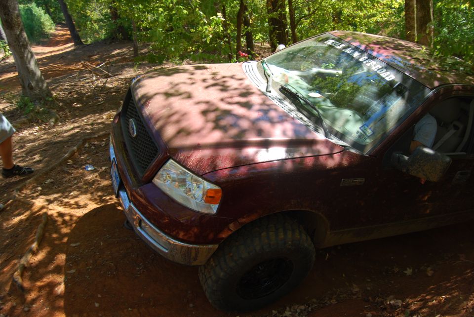 Maroon Ford F-150 on a dirt trail, front quarter view. Mud splattered on the body and tires