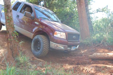 2005 Ford F-150 - This maroon 2005 Ford F-150 navigates a challenging dirt trail, its off-road capabilities.