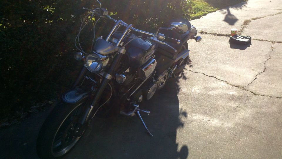 Dark motorcycle parked on cracked concrete, front 3/4 view