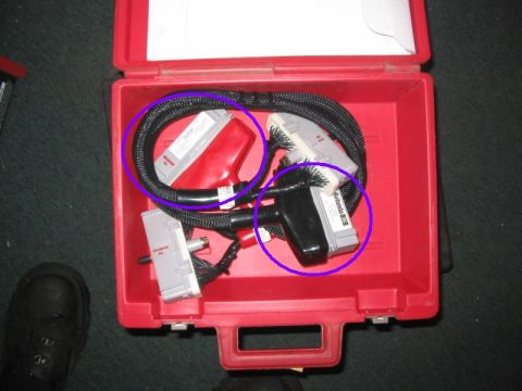 1994 Ford F-150 - Diagnostic cables and connectors are stored in a red plastic case, with some text visible on one connector.