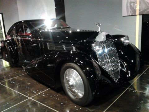 1995 Ford Taurus - A black vintage coupe with a distinctive chrome grille and hood ornament is displayed indoors.