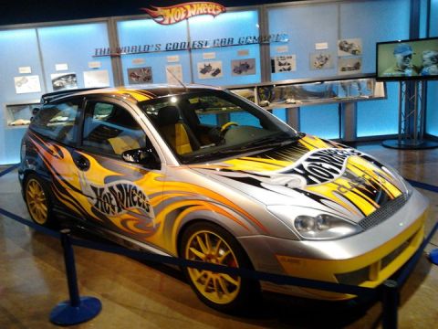 1995 Ford Taurus - Customized car with Hot Wheels branding and flame graphics on display at an exhibit.