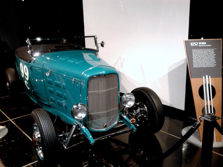 Teal 1932 Ford hot rod with white number 99 on the side, on display
