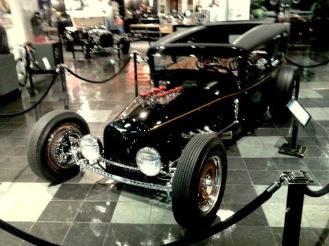1995 Ford Taurus - A custom hot rod with a powerful engine is displayed indoors, likely at a museum.