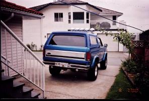 1985 Ford Bronco - This blue SUV is parked in a driveway with a house in the background.