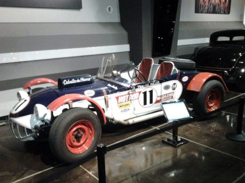 1995 Ford Taurus - A vintage open-wheel race car with racing decals and a spare tire mounted on the back is displayed indoors.