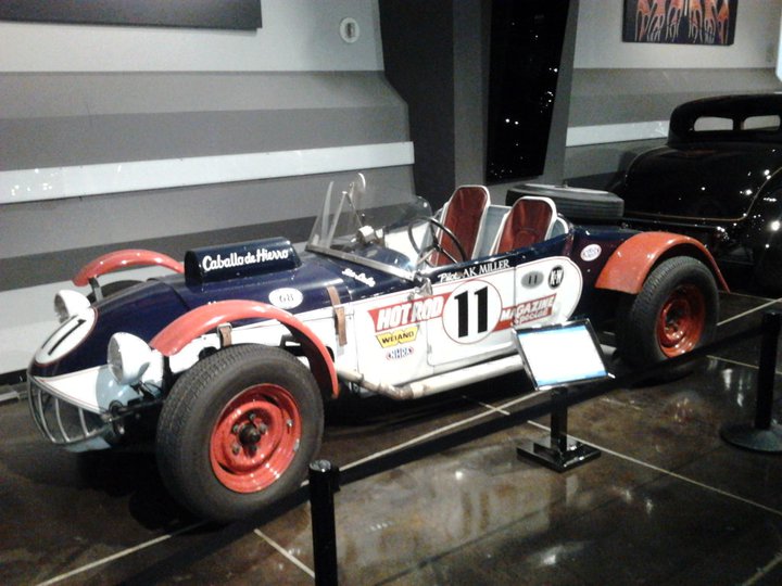 Open-top race car with blue body, red fenders, and number 11. Text includes 'Caballo de Hierro' and 'Hot Rod'