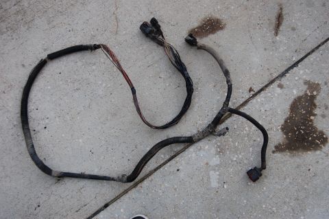 1994 Ford Bronco - A damaged wiring harness with exposed wires and connectors is shown on a concrete surface.