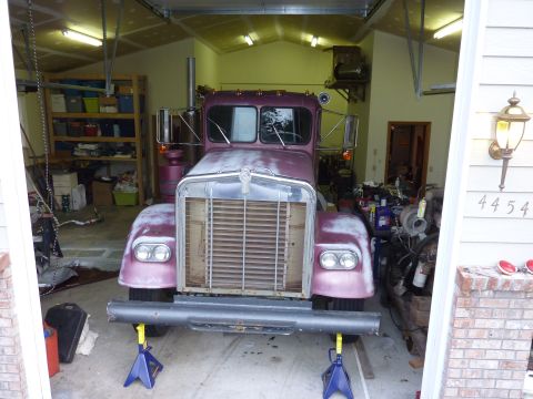 1959 Kenworth W900A - This semi-truck cab, painted purple and showing signs of wear, is elevated on jack stands inside a garage.