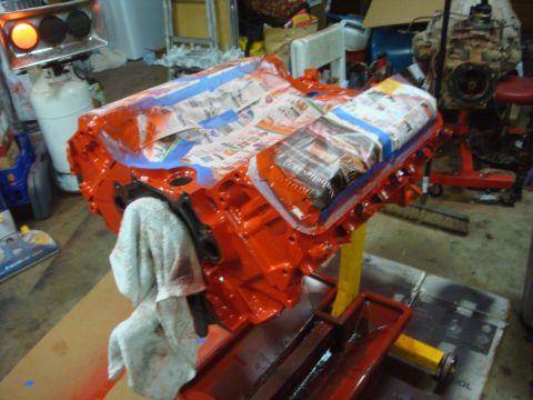 1989 Ford Bronco - An orange engine block is prepared for painting, with the intake manifold covered by newspaper and blue tape.