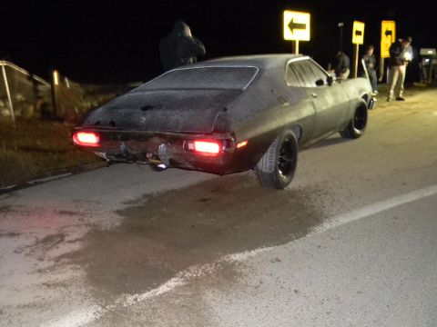 1975 Ford Ranchero - This 1975 Ford Ranchero shows its rear end, with a damaged bumper and glowing taillights, under the night sky.