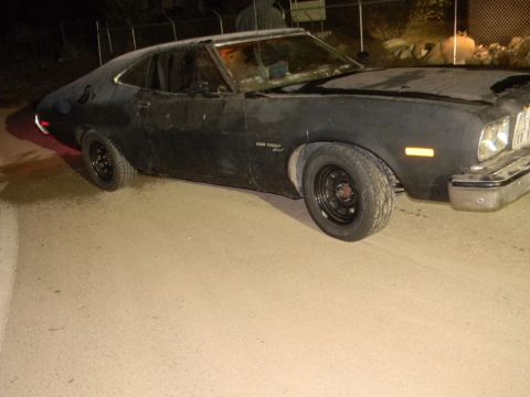 1975 Ford Ranchero - A black Ford Ranchero is parked on a dirt lot at night. The vehicle appears to be a 1977 model.