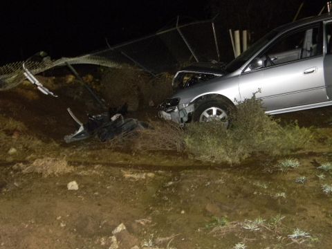 1975 Ford Ranchero - A silver sedan has crashed off the road and into a fence, with debris scattered nearby.