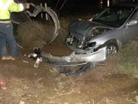 1975 Ford Ranchero - A severely damaged silver sedan sits off the road, its front end crumpled and parts scattered.