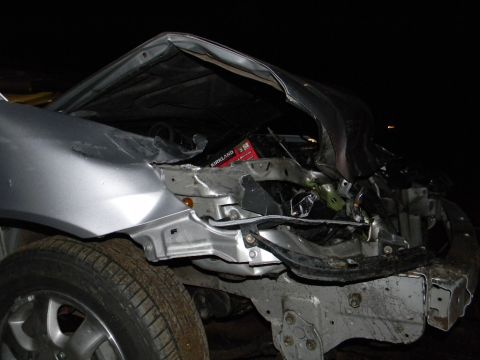 1975 Ford Ranchero - The front end of a silver car is heavily damaged, revealing crumpled metal and exposed engine components.