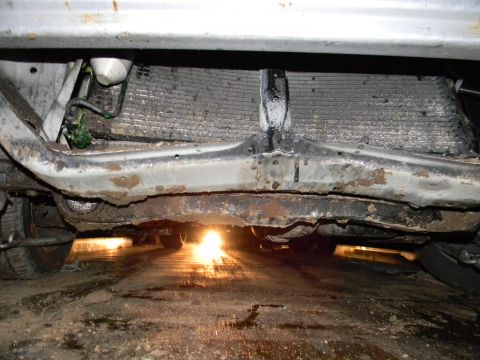 1975 Ford Ranchero - The underside of a vehicle reveals a dirty radiator and corroded frame components.