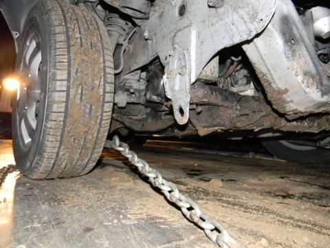 1975 Ford Ranchero - A heavy chain is secured to the frame of a vehicle, with the front tire visible.