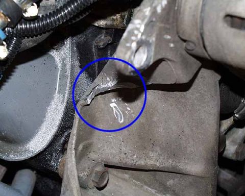 1990 Ford Bronco - Damaged metal engine component, possibly part of an alternator bracket.