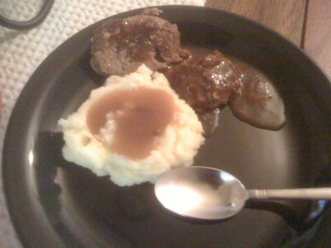 1968 Ford Mustang - A plate of meatloaf and mashed potatoes topped with gravy, with a spoon resting on the side.