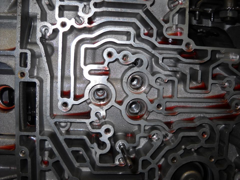 Close-up of automatic transmission valve body with red fluid in channels