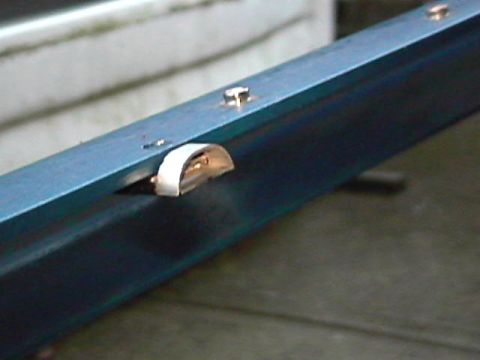 1985 Ford Bronco - A close-up view of a metal bracket with fasteners and a clip, likely a vehicle part.