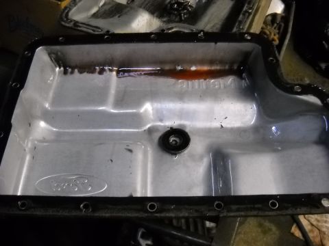 1993 Ford C-150 (Centurion Conversions) - Close-up of a Ford transmission pan showing dark fluid residue and the embossed Ford logo.