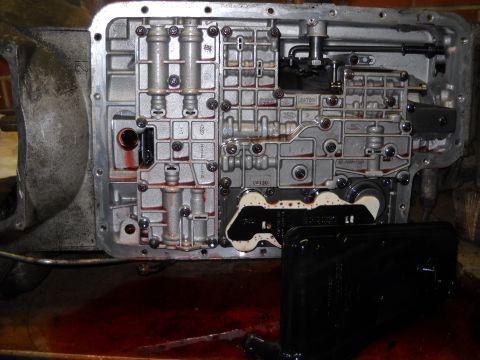 1993 Ford C-150 (Centurion Conversions) - The internal components of an automatic transmission valve body are visible, with transmission fluid spilled below.