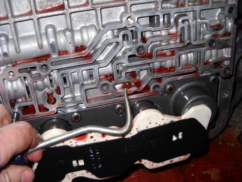 1993 Ford C-150 (Centurion Conversions) - Automatic transmission valve body internal view with red fluid and a tool.