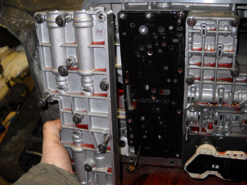 Close-up of a disassembled automatic transmission valve body with red fluid visible