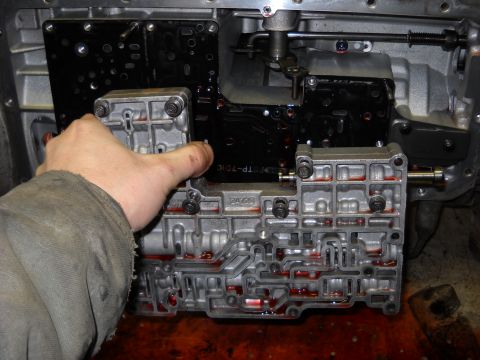 1993 Ford C-150 (Centurion Conversions) - Close-up of a transmission valve body being serviced, revealing intricate internal channels and fluid.