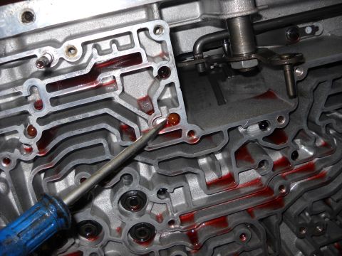 1993 Ford C-150 (Centurion Conversions) - Mechanic inspects the valve body of an automatic transmission, checking for fluid levels in the channels.