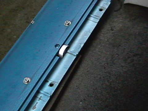 1985 Ford Bronco - Close-up view of a blue metal panel with visible screws and a silver clip mechanism.