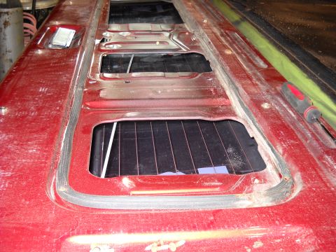 1993 Ford C-150 (Centurion Conversions) - The rear of a red vehicle, likely a tailgate, shows three rectangular openings where windows would be installed.