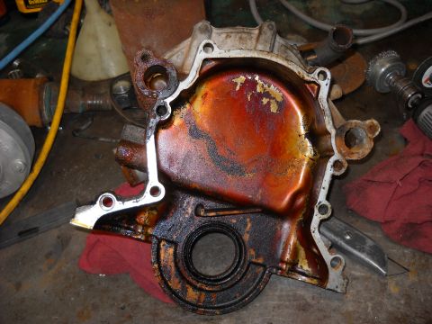 1993 Ford C-150 (Centurion Conversions) - A heavily soiled engine timing cover sits on a workbench amidst tools and rags.