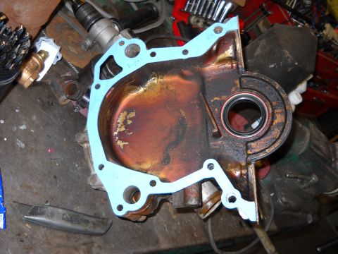 1993 Ford C-150 (Centurion Conversions) - Engine timing cover and gasket, likely for a Ford vehicle, on a workbench.