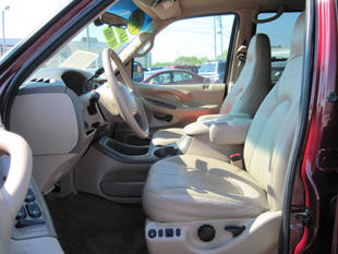1999 Ford Expedition - The interior of a red Ford Expedition is shown, tan leather seats and a dashboard.