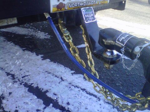 1994 Ford F-150 - Trailer hitch assembly with safety chains and a blue hose, seen on a snowy road in North Dakota.