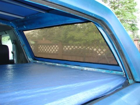 1985 Ford Bronco - View of the rear of a vehicle with a blue tarp and a mesh window.