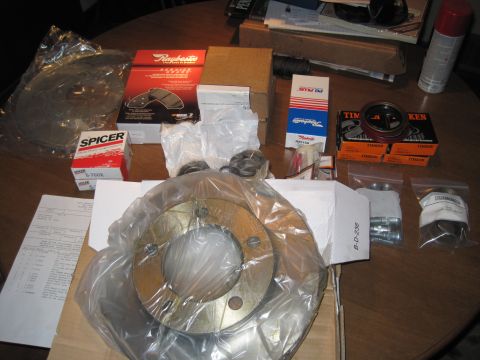 1979 Ford Bronco - A collection of new brake components, including rotors and pads, are organized on a wooden surface.