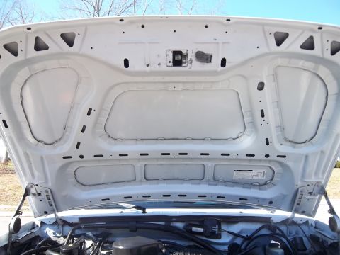 1995 Ford Bronco - The underside of a vehicle's hood is shown, revealing its construction and some engine parts.
