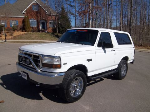 1995 Ford Bronco - This white 1995 Ford Bronco features a chrome bull bar and aftermarket wheels, seen parked in a residential driveway.